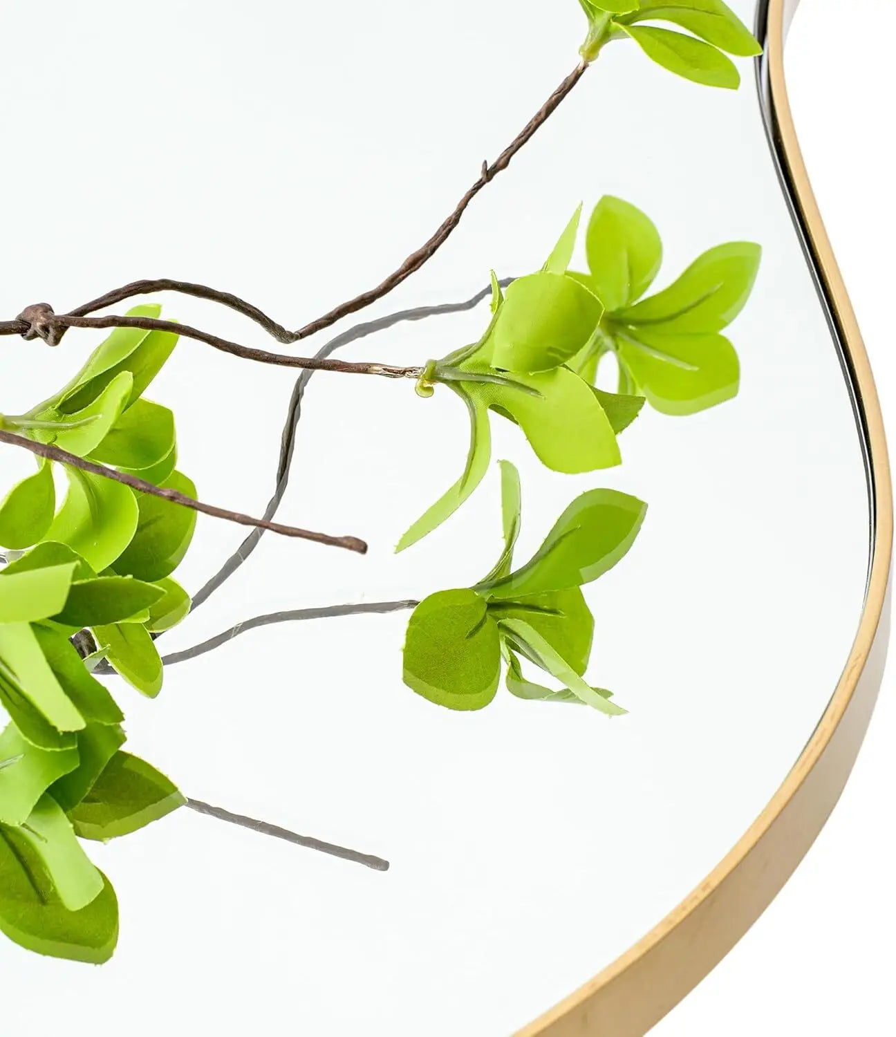 Close-up of the slim gold frame edge with green branches reflected