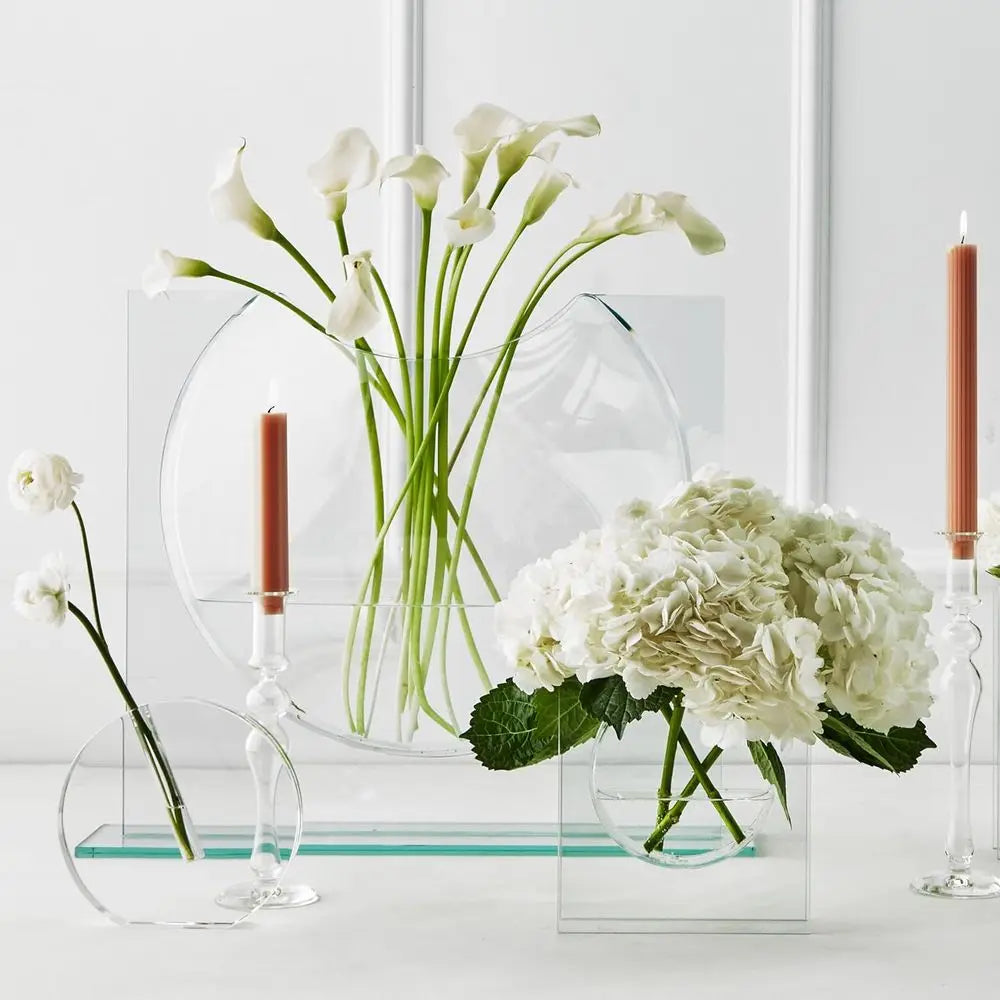 Clear glass ellipse vase with calla lilies beside candles