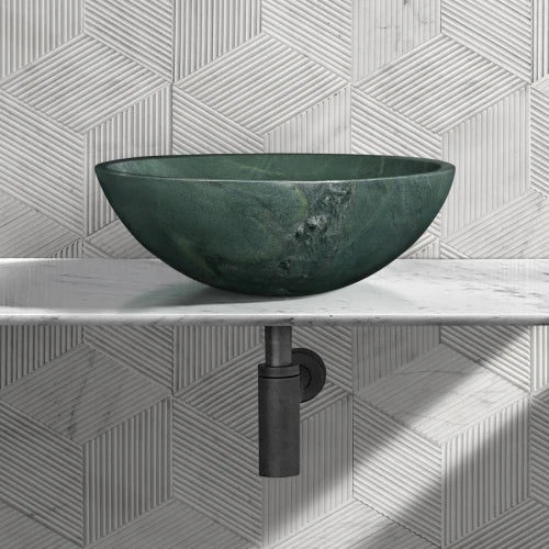 Polished green natural marble vessel sink on a white countertop with black drain