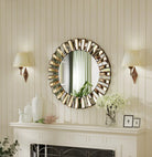 Round starburst wall mirror above a white mantel between two wall sconces
