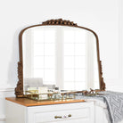 Arched antique gold baroque mirror with beaded frame and carved corners above a white dresser