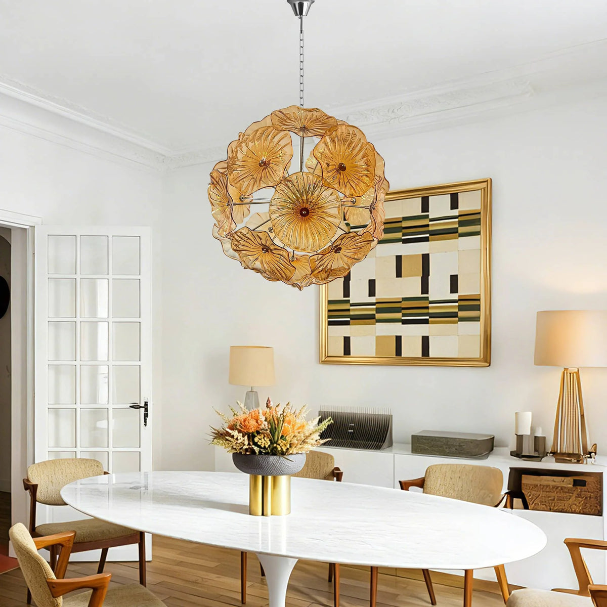 Amber glass flower chandelier over a white oval dining table