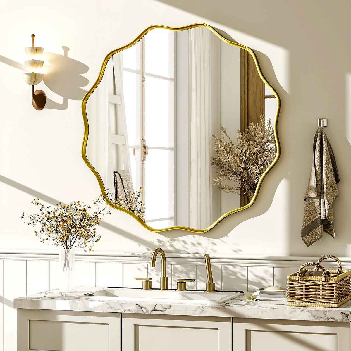 Scalloped round gold mirror reflecting a window above a white shaker bathroom vanity