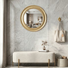 Brushed gold round mirror above an entryway bench
