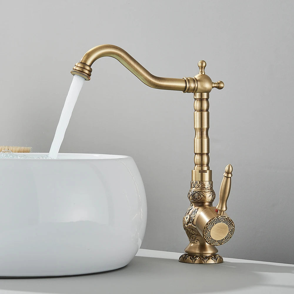 Carved antique brass swivel basin faucet over a white vessel sink