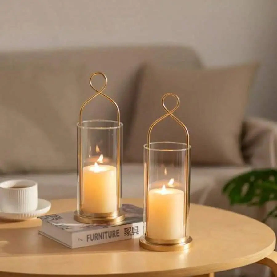 Gold sconce hurricanes with glass shades and pillar candles on a side table