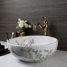 Flower-and-bird porcelain vessel sink on a white counter with gold faucet