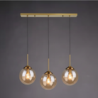Three amber glass globe pendants on a brass linear canopy