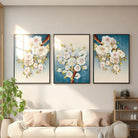 White blossom branch framed wall art, set of 3, above a sofa