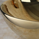 Close-up of the mirror-like polished gold glaze on the round ceramic vessel sink rim