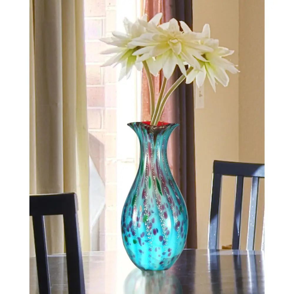 Teal art glass vase with white flowers on a dining table