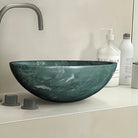 Close-up of the polished green marble vessel sink showing white veining on a counter