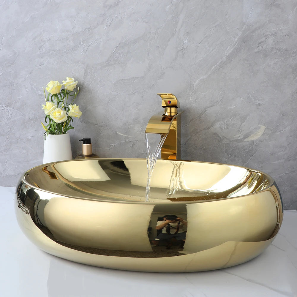 Gold oval vessel sink with waterfall faucet running