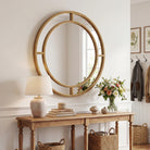 Round gold beaded mirror above an entry console