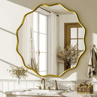 Wavy scalloped round wall mirror with gold frame above a marble bathroom vanity