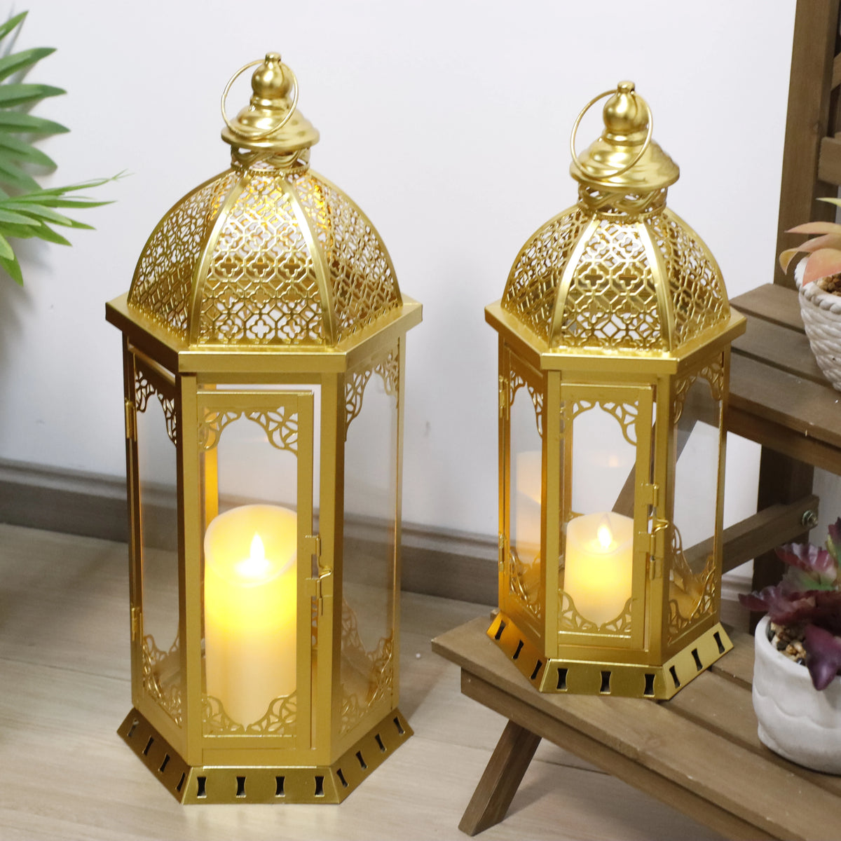 Set of two gold Moroccan candle lanterns with filigree domes and glass panels (on a bench)