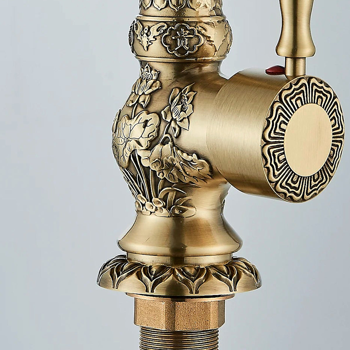 Close-up of the high-relief floral carving and scalloped flange on the antique brass faucet body