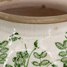 Close-up of the unglazed tan rim and green vine pattern on the crackled cream glaze