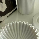 Close-up of the deep accordion pleats radiating inside the white ceramic bowl