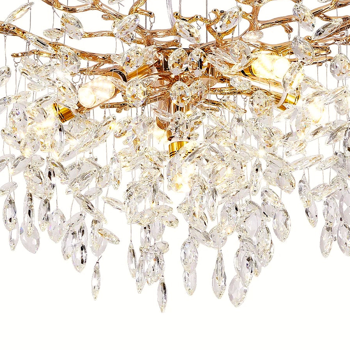 Close-up of the cascading faceted crystal strands catching warm light on the gold branch chandelier