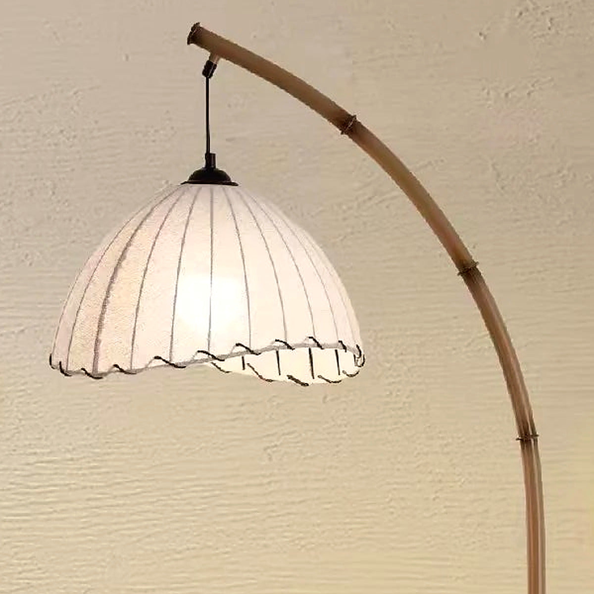 Close-up of the white pleated fabric shade with scalloped trim hanging from the bamboo arc