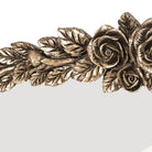 Detail of layered brass leaves and rosebuds along the left side of the baroque crest
