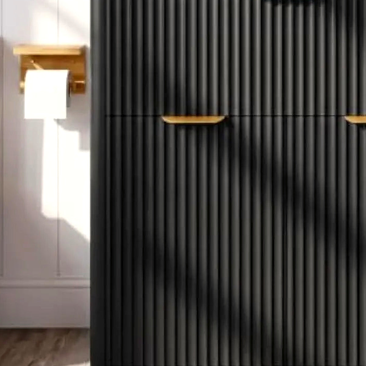 Detail of the left gold pull against the matte black fluted cabinet face