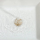 Close-up of the white ceramic basin and gold rim with running water