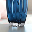 Close-up of the thick clear glass base grounding the blue-teal vase