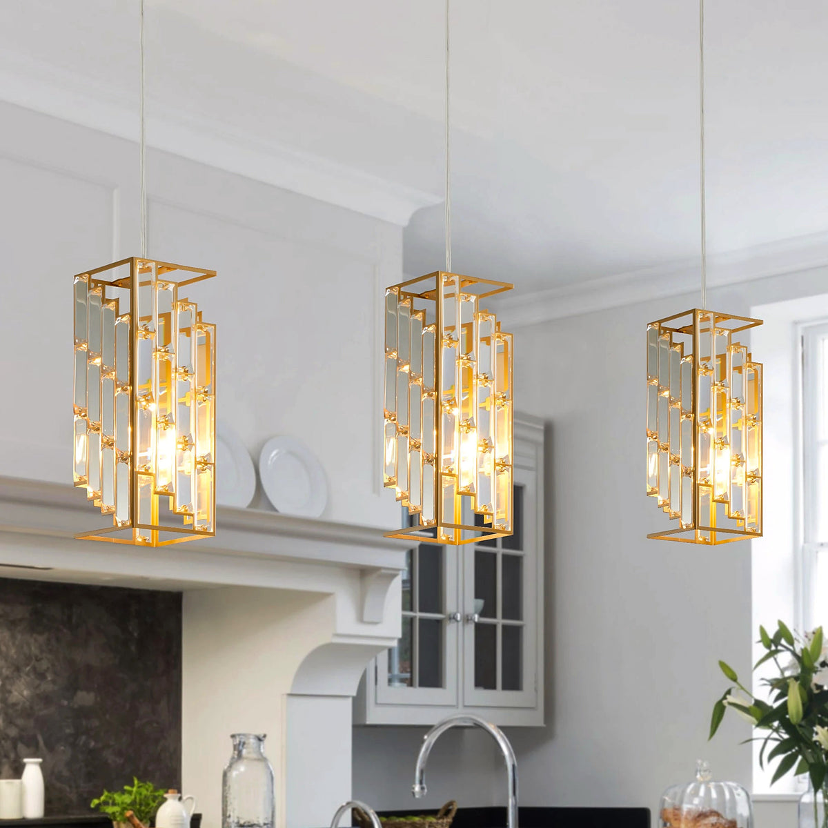 Gold crystal prism pendant lights, set of three, hanging over a white kitchen counter