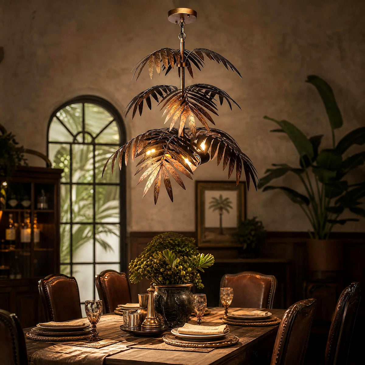 Bronze palm tree pendant chandelier over a set dining table in a tropical-inspired room
