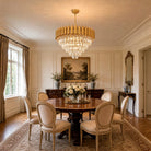 Gold five-tier raindrop crystal chandelier over a round dark wood dining table (furniture and décor shown for styling)
