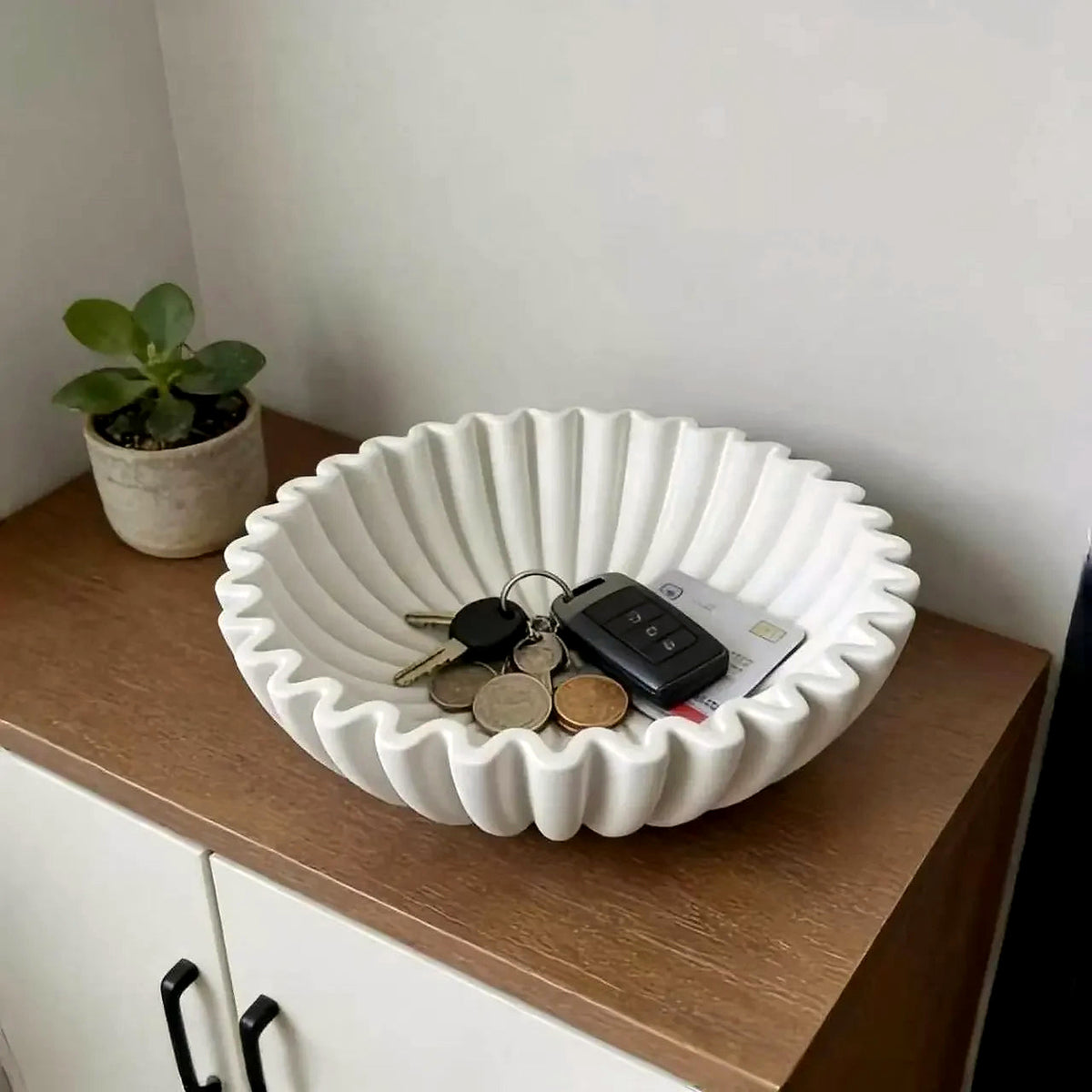 White pleated ceramic bowl used as a catch-all on a cabinet (keys and plant shown for styling)