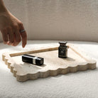 Scalloped travertine tray styled with lipstick and perfume (cosmetics shown for styling)