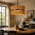Natural rattan drum pendant above a dining table (furniture and décor shown for styling)