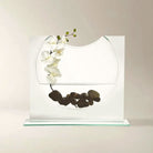 Clear glass ellipse vase with a white orchid and black river stones (orchid and stones shown for styling)