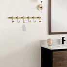 Brushed brass six-hook towel rail mounted above a bathroom vanity (vanity and décor shown for styling)