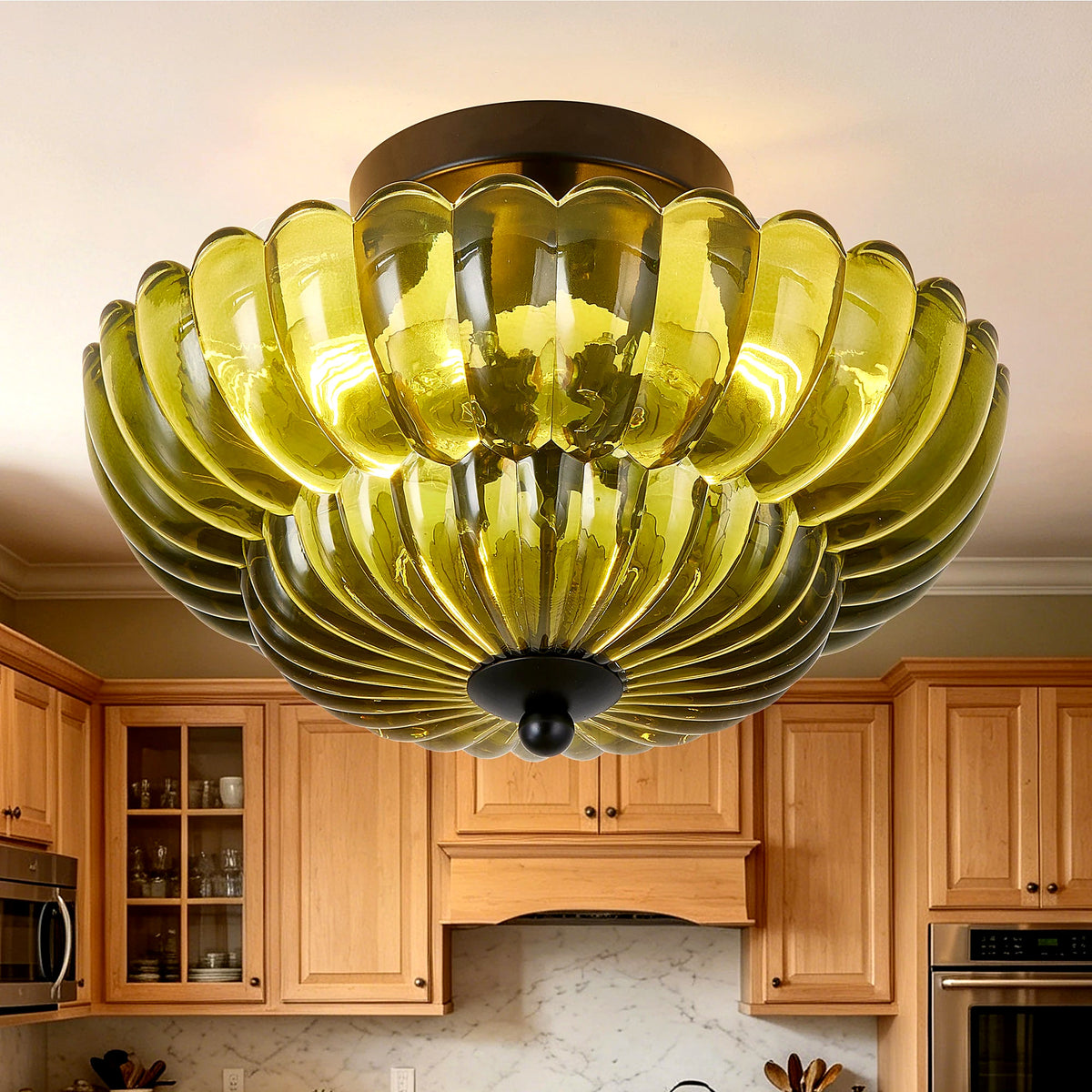 Olive-green petal glass semi-flush light glowing in a kitchen (cabinetry shown for styling)