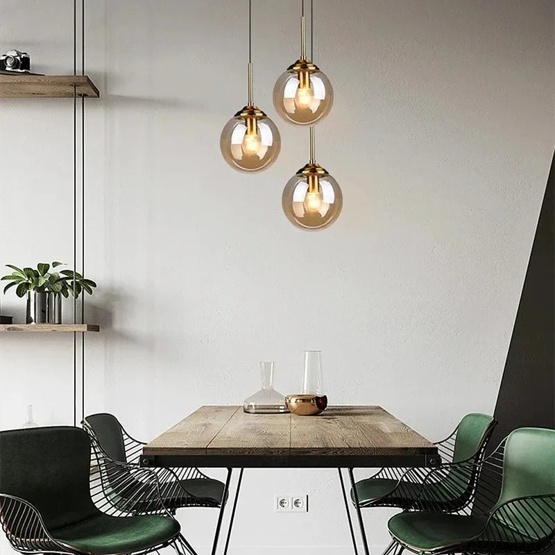 Three amber glass globe pendants hung at staggered heights