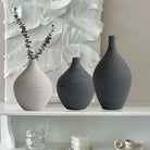 Beige and grey textured ceramic bud vases with eucalyptus on a white shelf