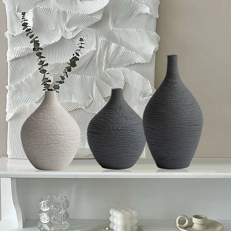 Beige and grey textured ceramic bud vases with eucalyptus on a white shelf