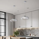 Two clear cloud glass pendant lights hanging over a white kitchen island