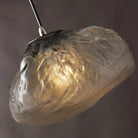 Close-up of a lit blown cloud glass pendant shade showing its rippled texture